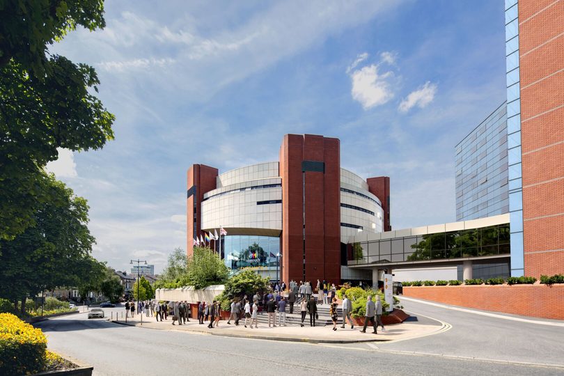 visitors in business attire walking into an large round building