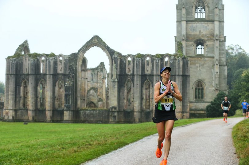 A runner passing by ancient ruins and lush greenery.