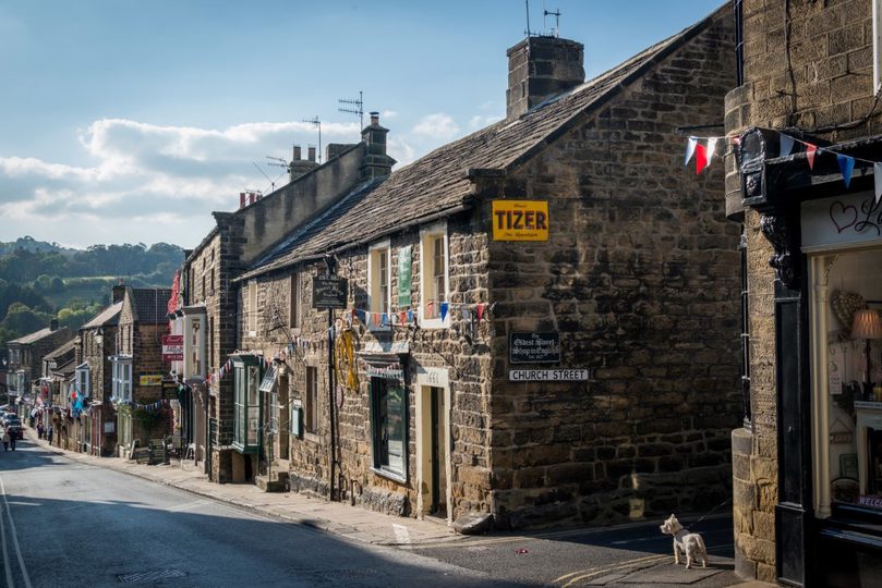 A sloping street lined by 2-story houses and bunting