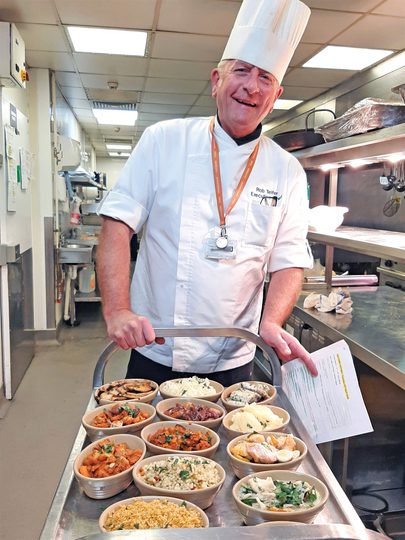 A chef proudly presents a tray of delicious food