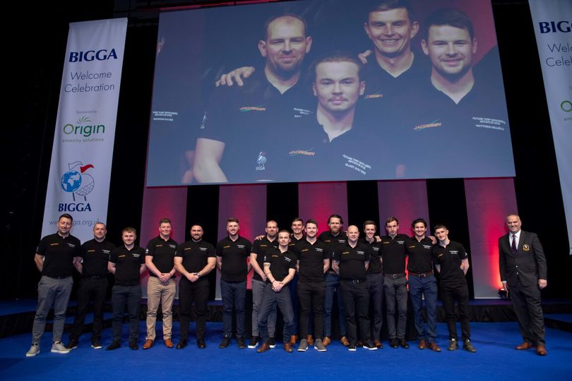 A group of men posing in front of a large screen at Harrogate Convention Centre