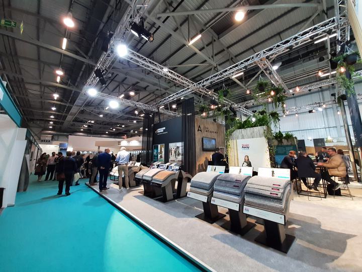 A spacious hall filled with people gathered around, attentively observing a display in the centre.