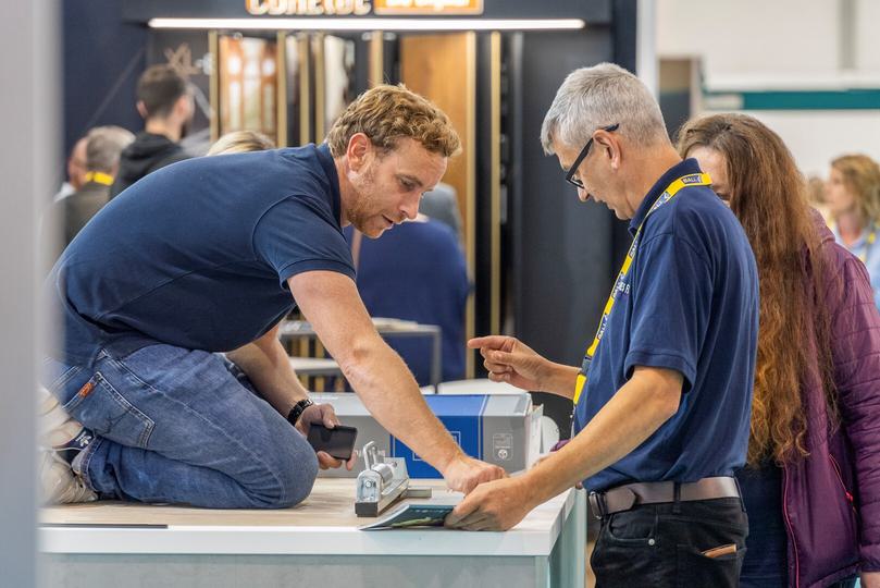 A carpet fitter interacting with a visitor at an exhibition stand